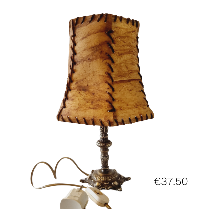 Varkensleer lamp met koperen poot. De kap is met de hand gestikt met een decoratieve vetersluiting, wat een rustieke en ambachtelijke uitstraling geeft.
