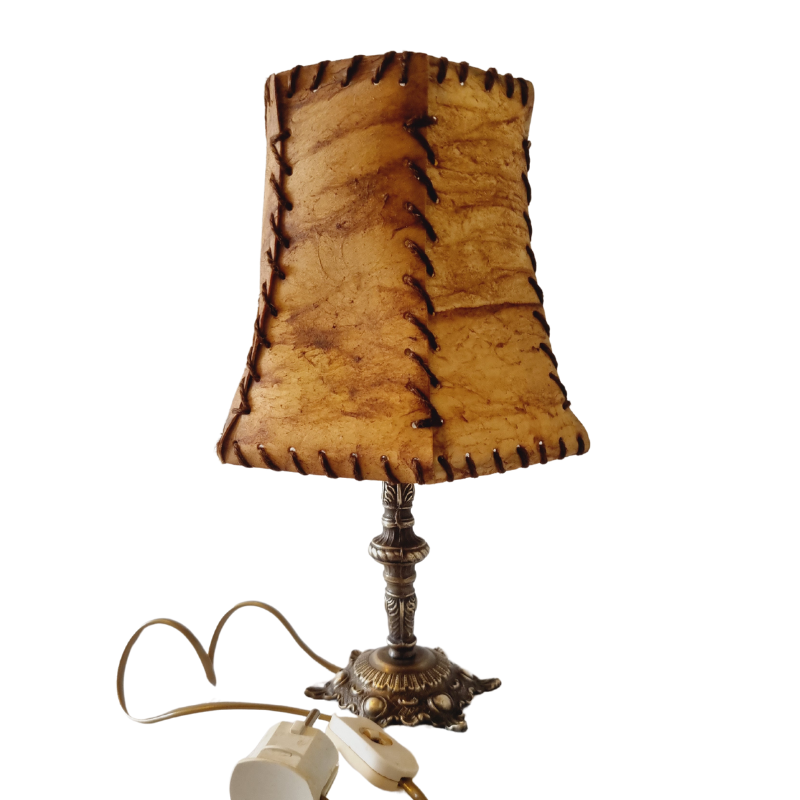 Varkensleer lamp met koperen poot. De kap is met de hand gestikt met een decoratieve vetersluiting, wat een rustieke en ambachtelijke uitstraling geeft.